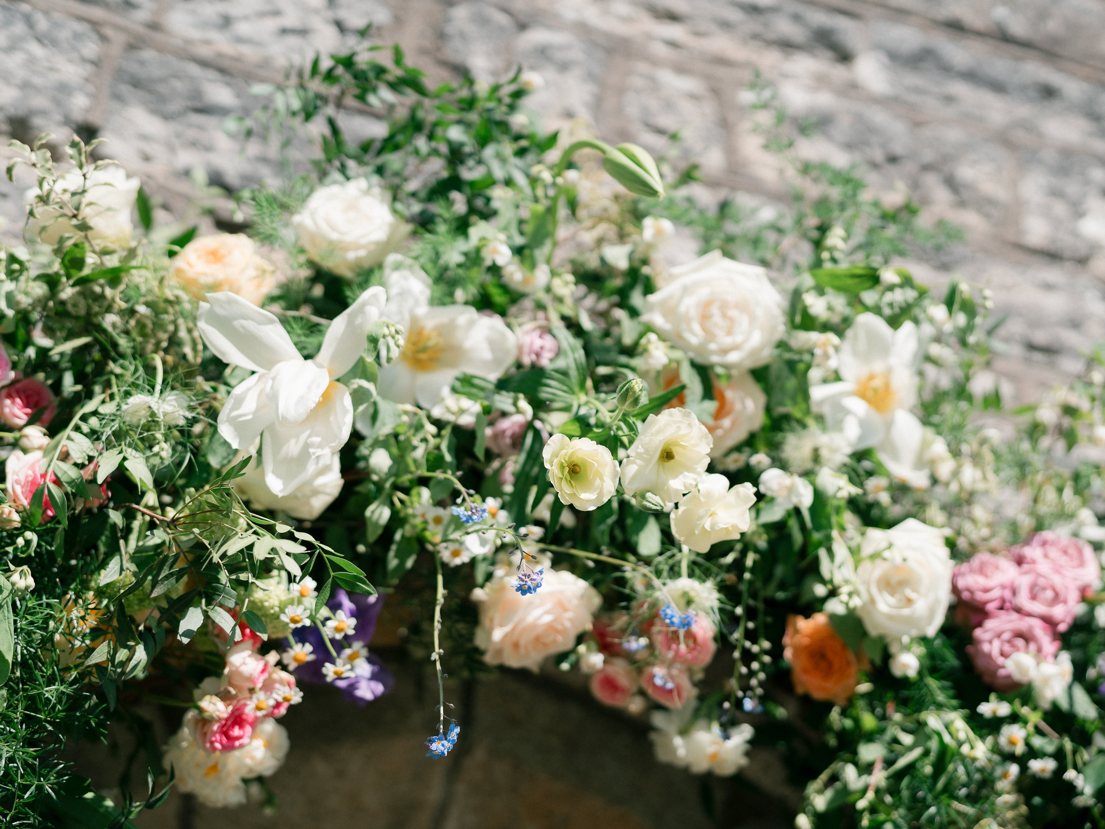 A bridal archway against a grey brick wall, with neutral blooms and a hint of pink
